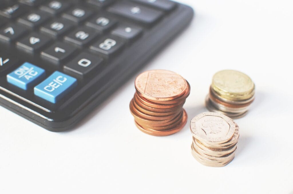Calculator and stacked coins representing the cost breakdown behind live transfer mortgage leads