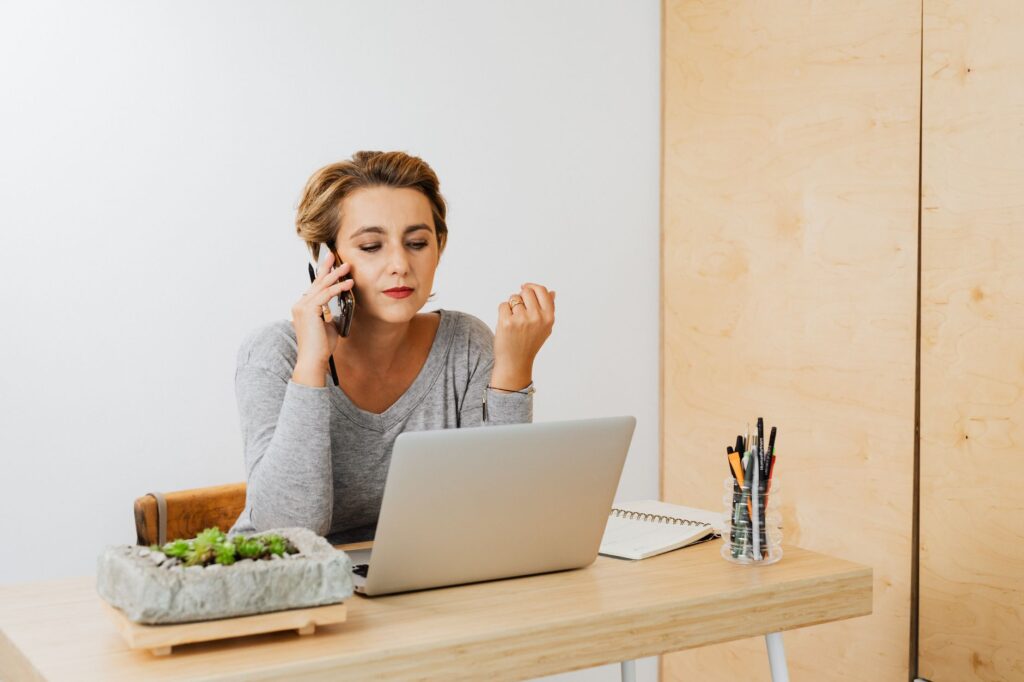 Loan officer on phone with laptop working refi lead follow-up from existing book of business
