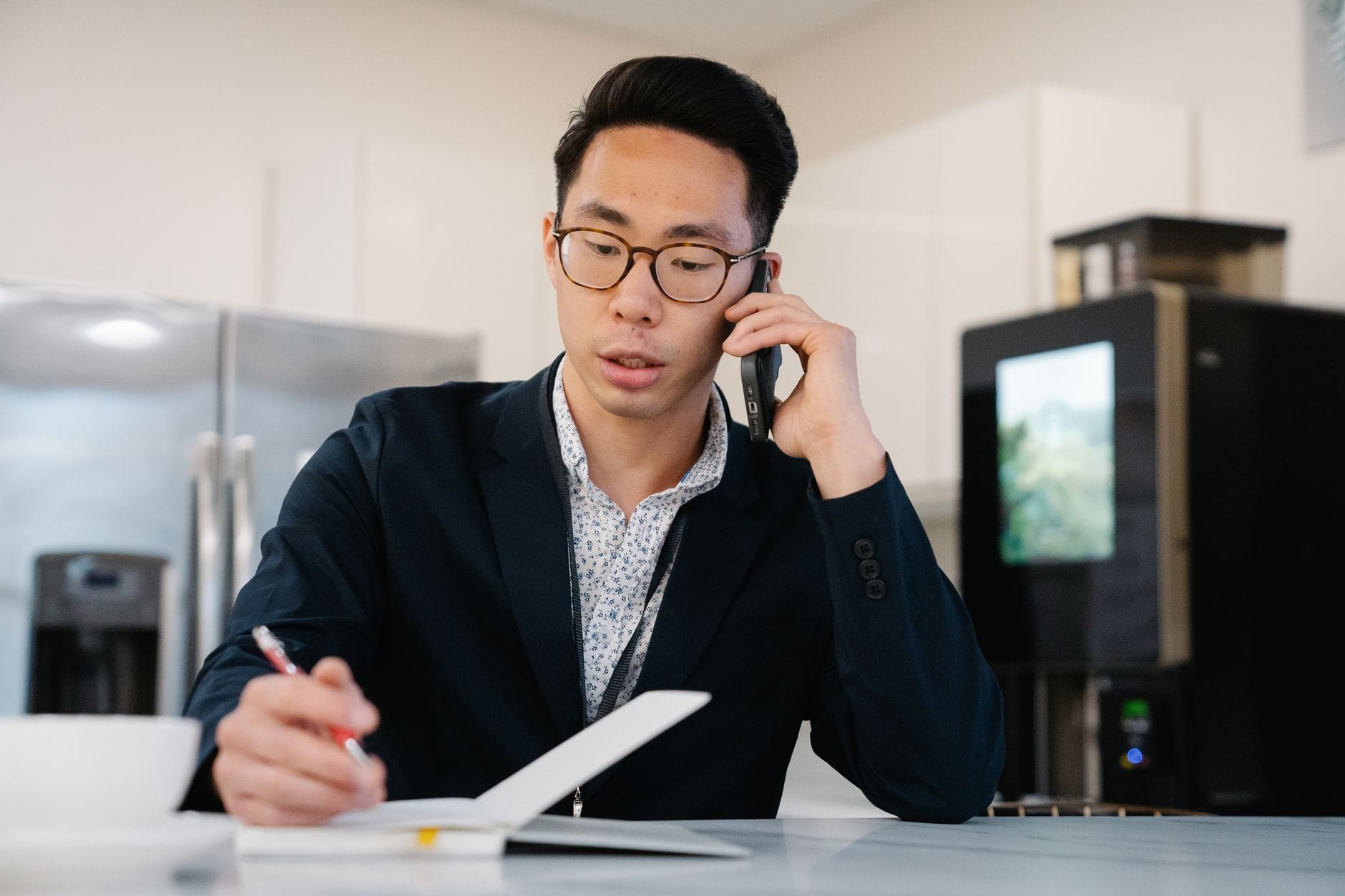 Loan officer on the phone taking notes while reviewing mortgage leads at his desk