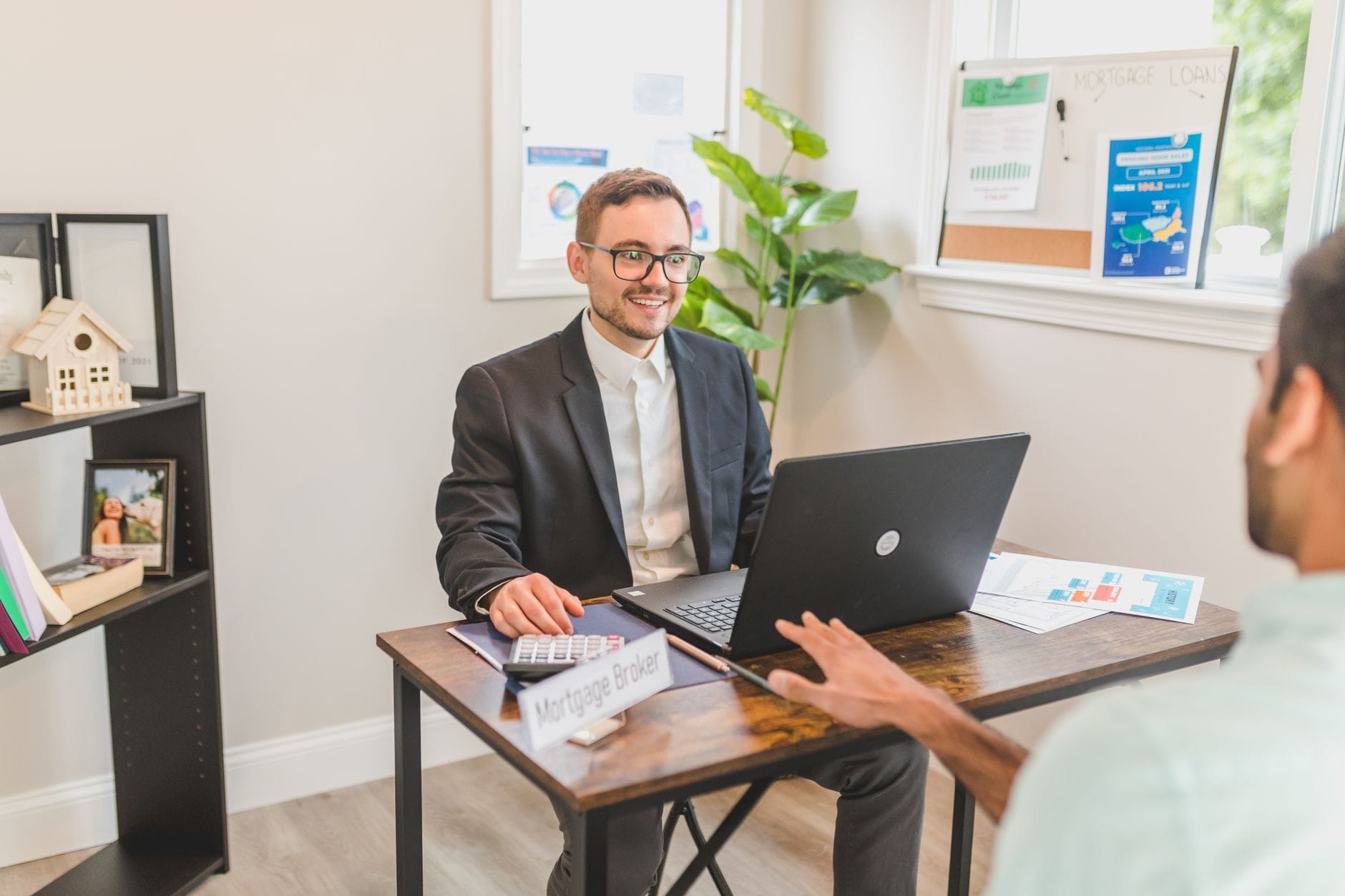 Mortgage broker at desk with laptop reviewing lead options with a client. Photo by Pexels.