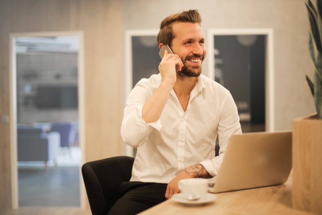 Loan officer smiling on phone call with laptop open, working a multi-touch lead follow-up cadence