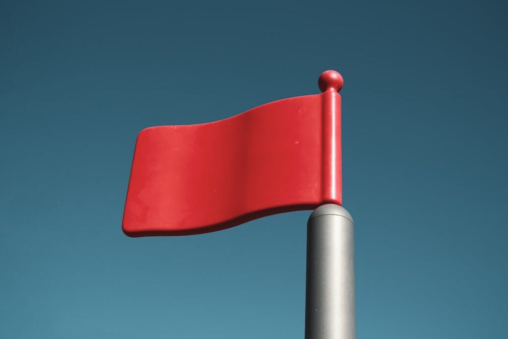 Red flag on a pole against a clear blue sky, representing red flags in mortgage lead pricing