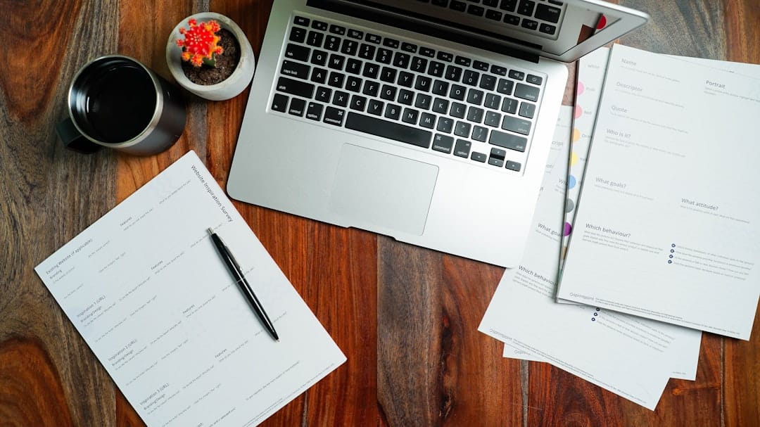 Laptop and mortgage documents spread on a wooden desk, representing loan officer lead cost analysis