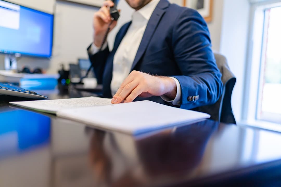 Loan officer on phone at desk reviewing mortgage documents — photo by Unsplash