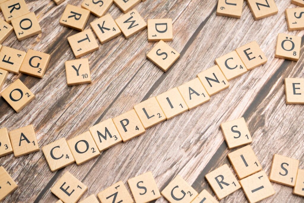 The word compliance spelled out in Scrabble tiles representing TCPA compliance requirements for aged mortgage leads
