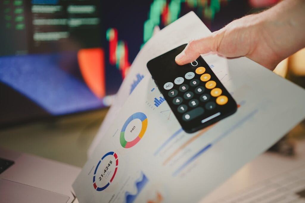 Calculator held over financial performance charts, illustrating mortgage lead pricing analysis
